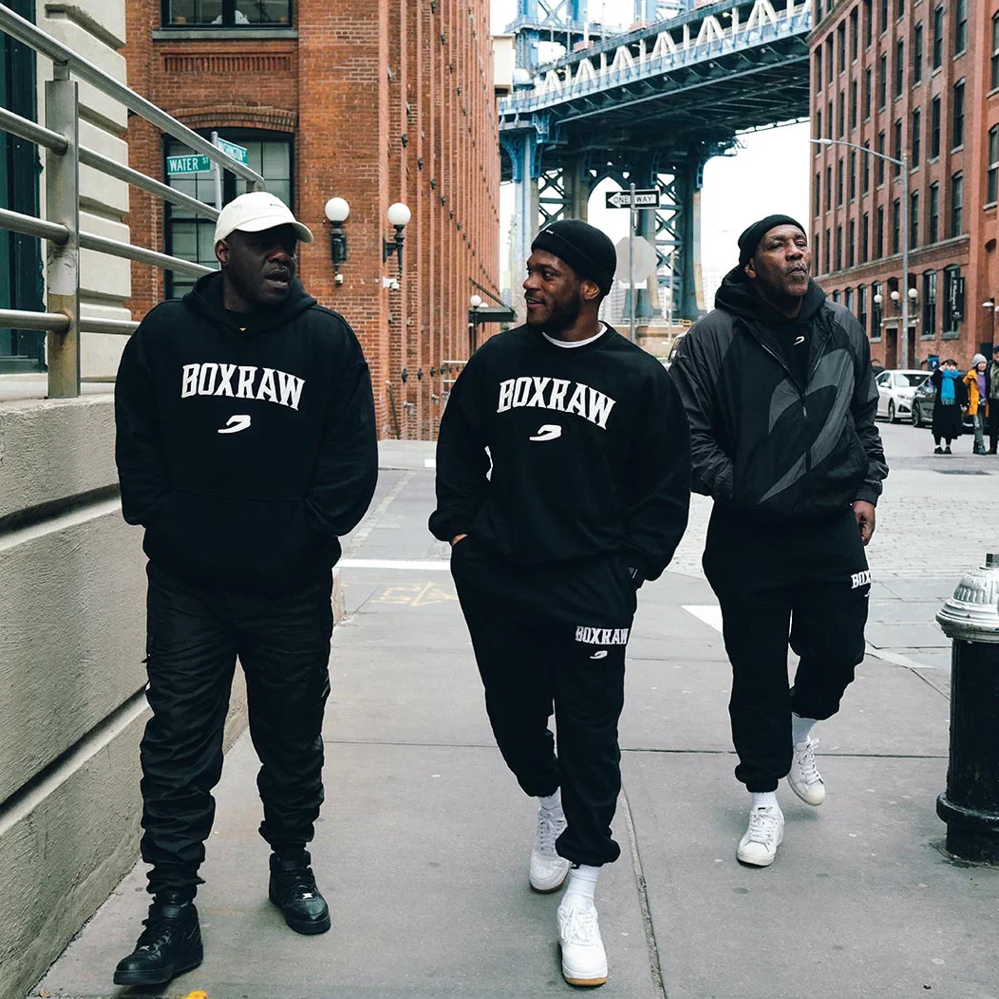 image of 3 men walking in new york wearing boxraw east street hoodie black with white logo